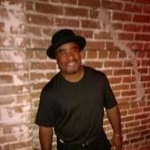 Anthony "Lucky" Breach in a black hat in front of a brick wall