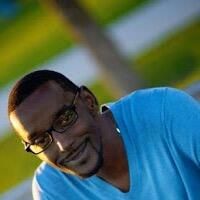 Stephen Holcomb smiling, wearing glasses and a blue shirt