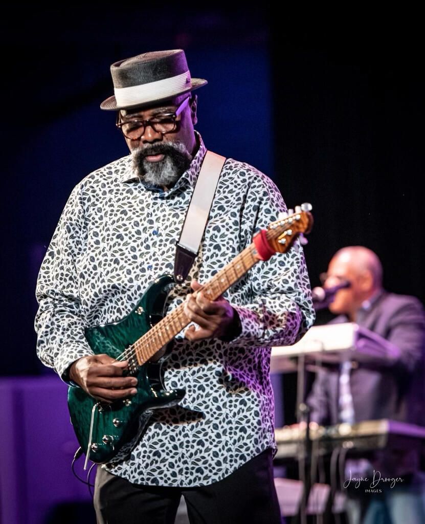 Willie Thompson playing a green electric guitar on stage